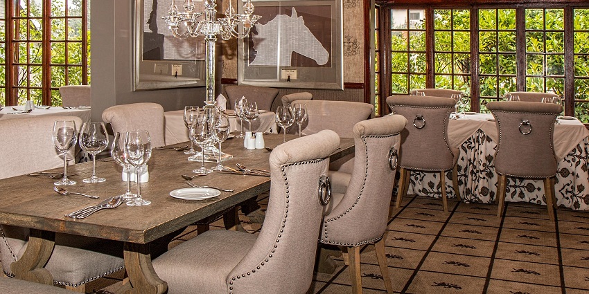 An image showing dining tables with white chairs neatly arranged inside a restaurant.