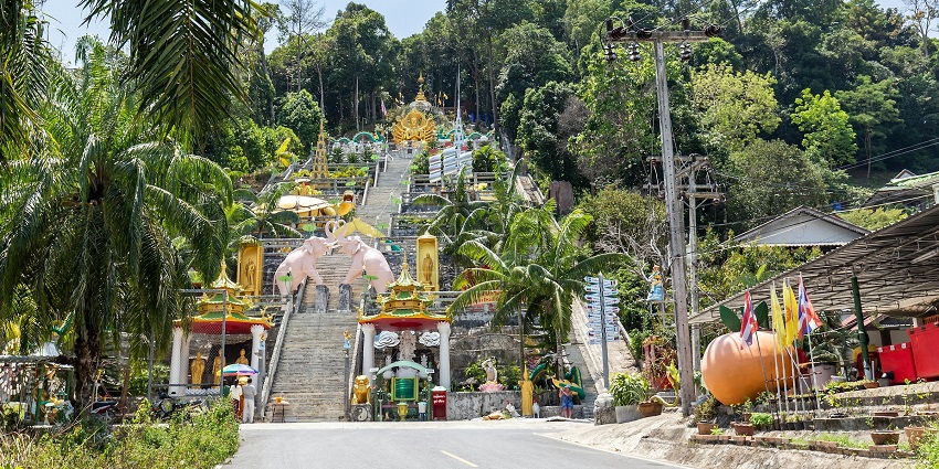 View of a temple in Krabi Town surrounded by greenery and hills.
