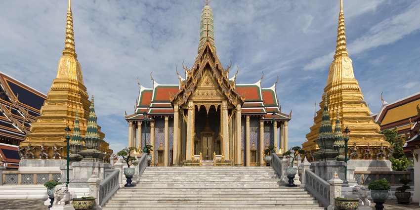 Ornate temple structure with golden details and playful monkeys roaming the grounds near the riverbank, one of the best things to do in Nakhon Sawan.
