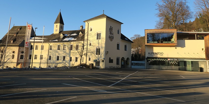 Entrance of Alpenzoo in Innsbruck, featuring a welcoming sign and scenic mountain views.