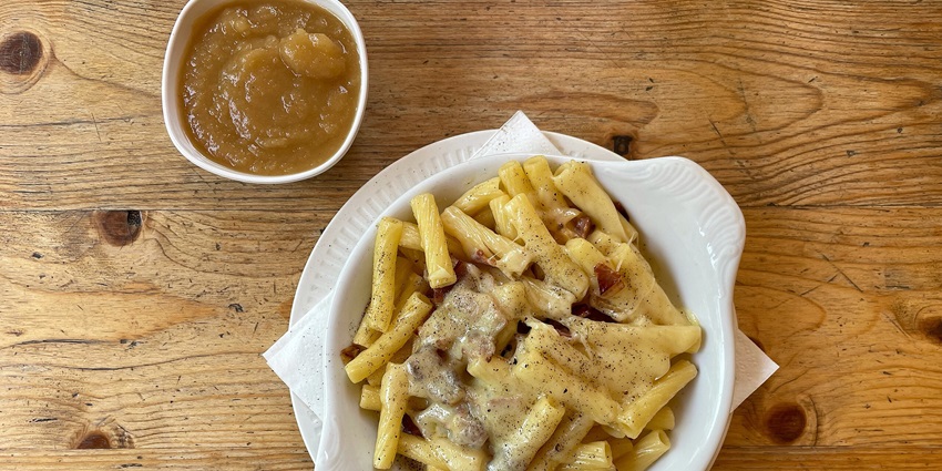 An image showing Älplermagronen, a Swiss pasta dish with cheese, potatoes, and caramelised onions.