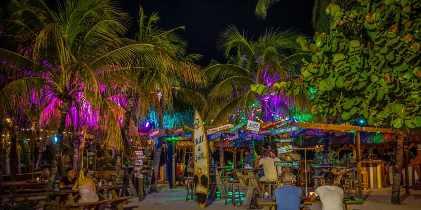 A picture of a beach shack with people enjoying the dim ambience at night