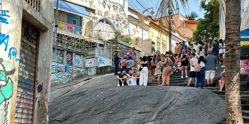 Crowd gathered around musicians playing samba at night in a graffiti-covered square with colorful lights and caipirinhas in hand, one of the best things to see in Rio De Janeria at night.
