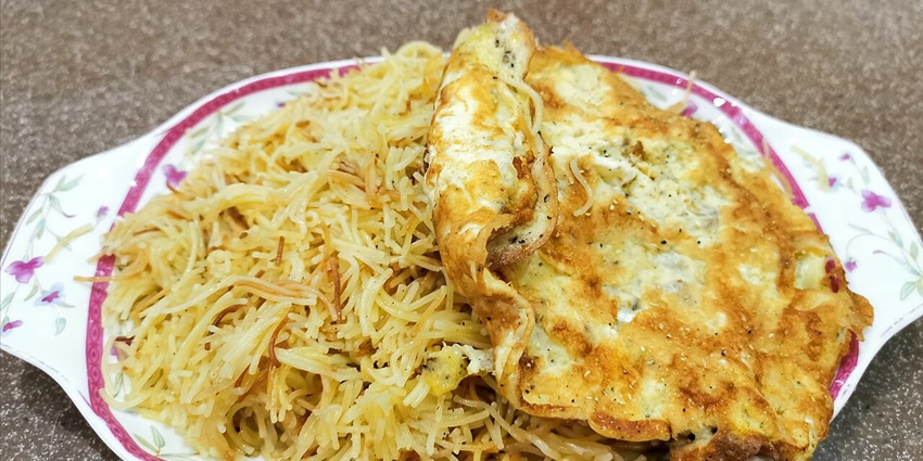 An image of Balaleet, a famous Qatari breakfast dish with vermicelli noodles and a fried egg.