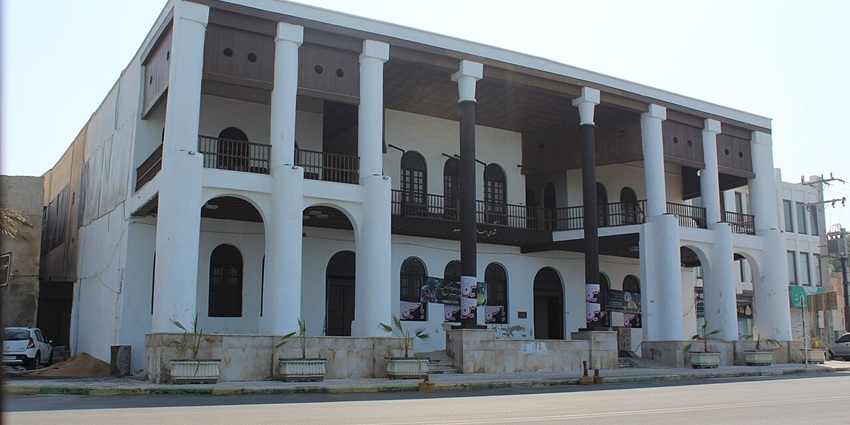 Two-storey Qajar-era Amiriyeh Mansion with coral-stone walls and wooden balcony.