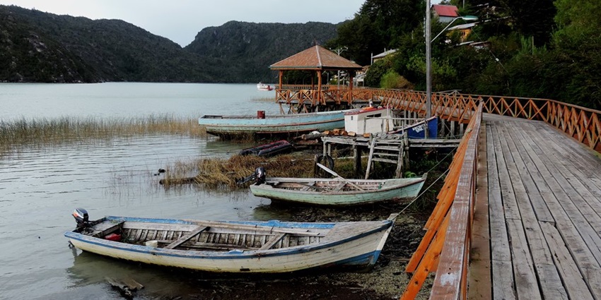 Scenic view of Caleta Tortel village with wooden walkways, stilt houses, and surrounding lush hills in Chilean Patagonia.