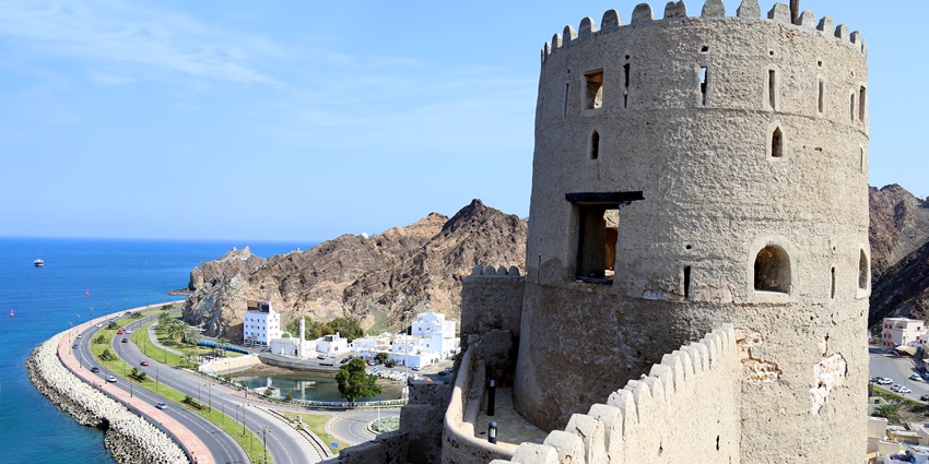 Fort Mutrah illuminated at night overlooking Muscat cityscape and harbor in Oman