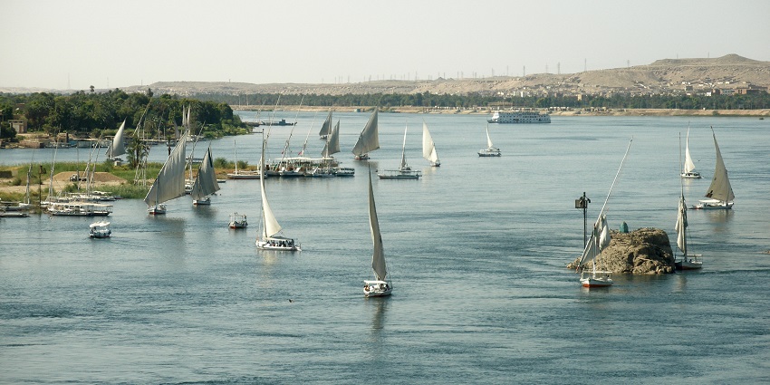 Feluccas sailing peacefully on the Nile River near Aswan under a warm Egyptian sky