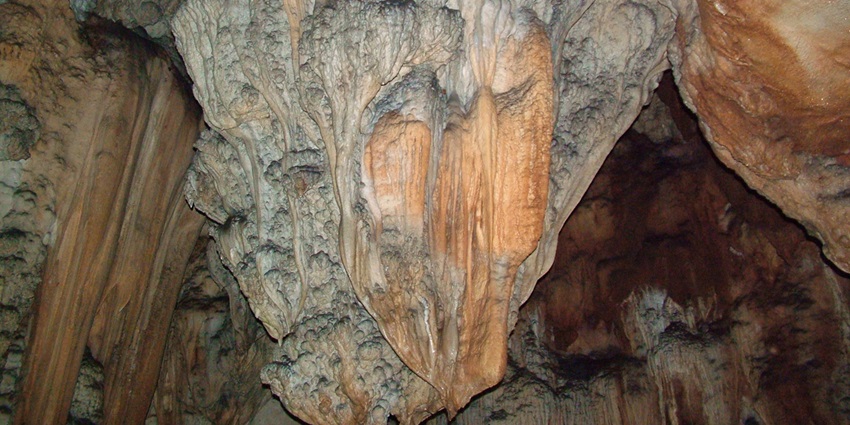 Stone stairway leading to the entrance of Bo Ya Cave, surrounded by forest and dotted with small shrines.