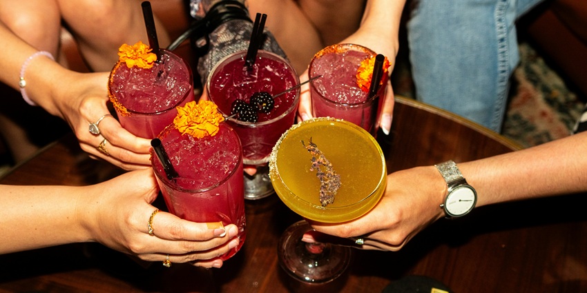 Image of a group of friends doing cheers with their colourful drink on hand