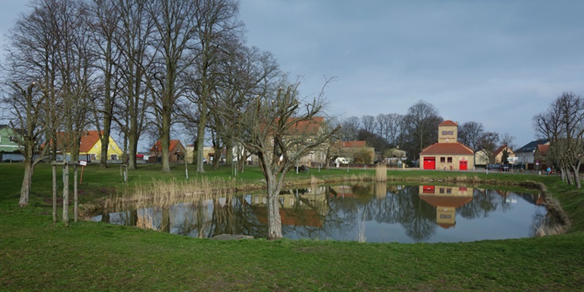 A heavenly view of the countryside during winter with barrenness all around and a little pond.