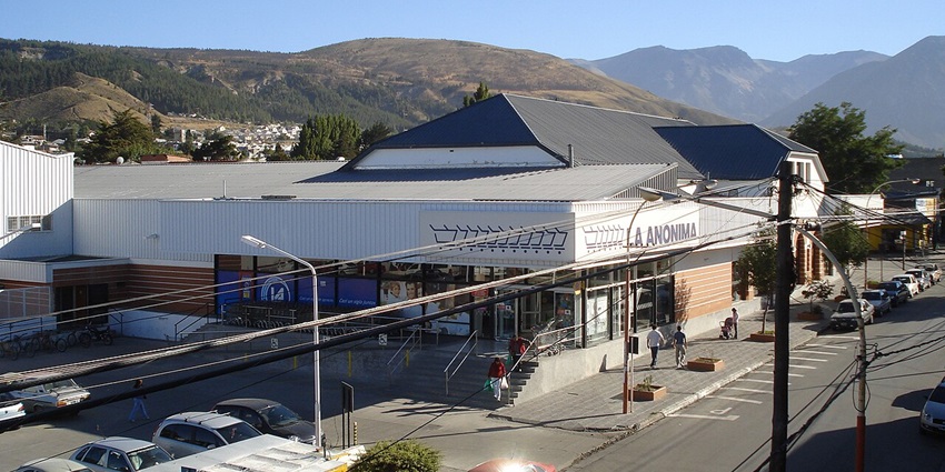Exterior view of a La Anónima supermarket, a popular grocery chain in Argentina, with parked cars and clear skies, one of the best places to visit in Patagonia Argentina