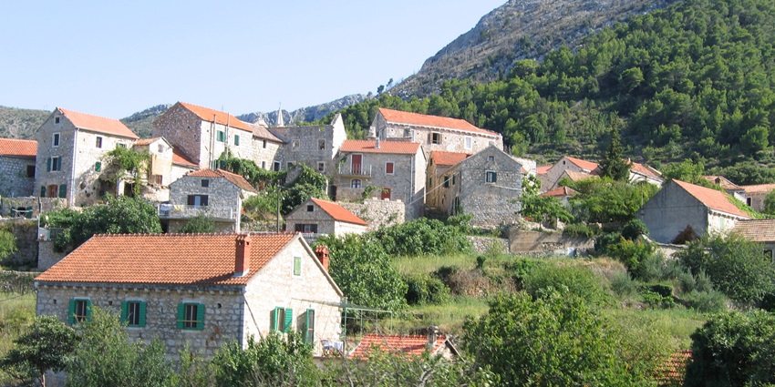 A scenic view of the rustic stone houses of Pitve village in Hvar, nestled in green hills with traditional charm and historic appeal, one of the best things to see in Hvar.