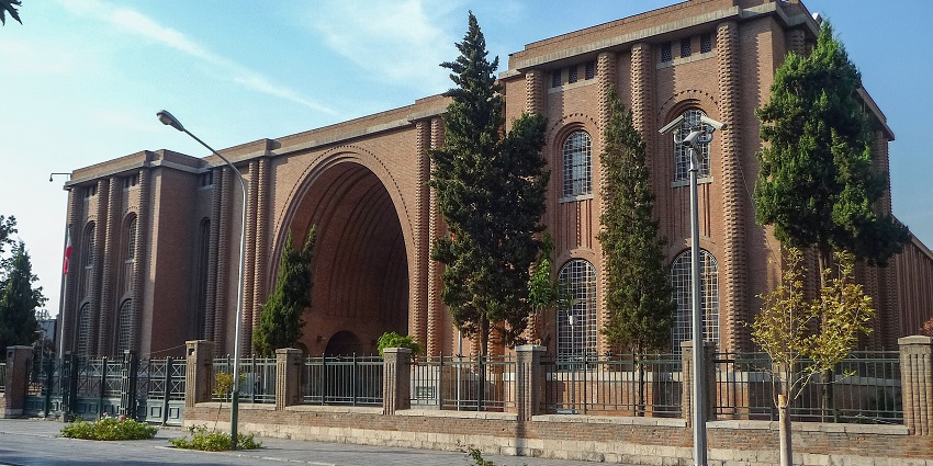 The National Museum of Iran's exterior features a grand brick with a large central arch.