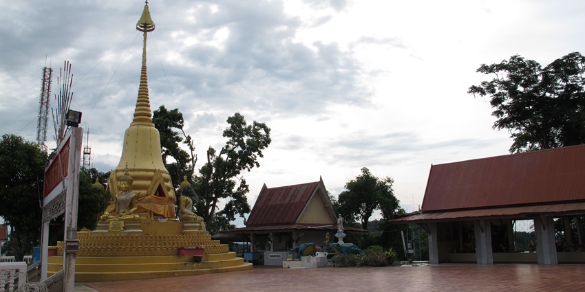 Visit hilltop temple with a golden Buddha statue surrounded by lush greenery, one of the best things to do in Nakhon Sawan.
