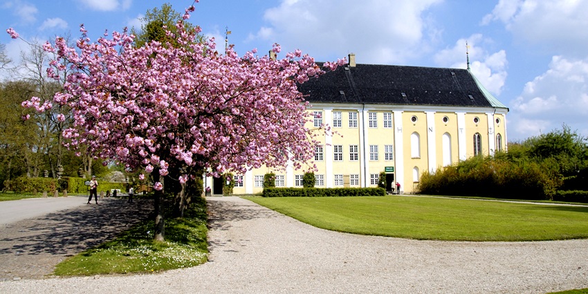 Image of Gavnø Castle's Rococo façade framed by vibrant spring blooms in the garden.