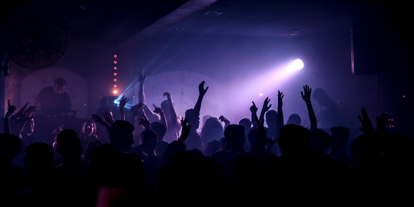 Crowded boliche with flashing lights, dancing people, and a lively DJ in Buenos Aires.