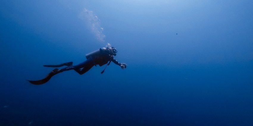 Man under the ocean wearing scuba gears and oxygen cylinder`