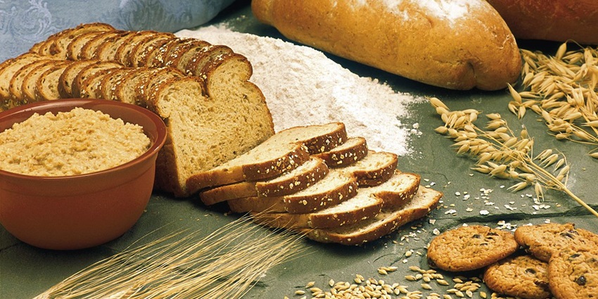 Display of assorted whole grains in bowls and sacks on a table, rich textures and colours