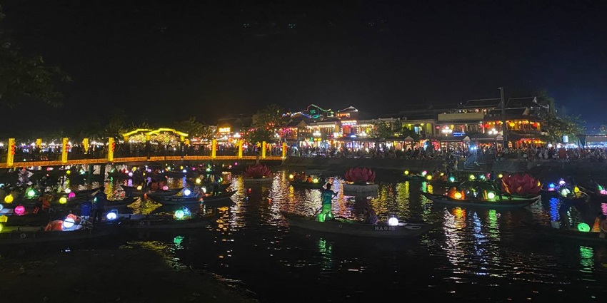A picture of a waterfront night market in Vietnam with lanterns and a bustling crowd