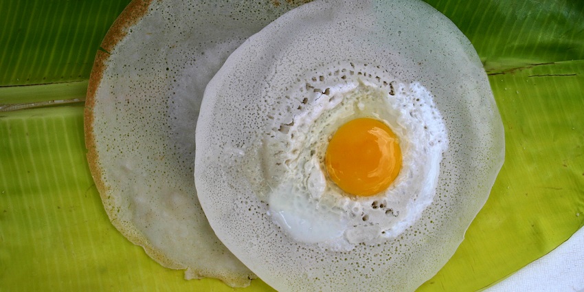 South Indian egg appam with a soft centre served hot on a fresh green banana leaf