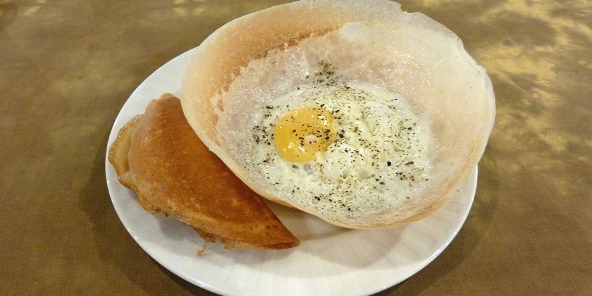 A plate of crispy hoppers, the best food in Sri Lanka, with bowl-shaped pancakes with egg.