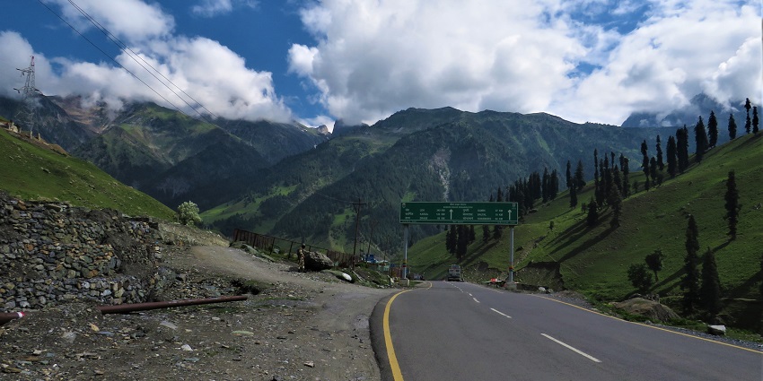 Srinagar Leh National Highway-1 with a tall green sign board surrounded by green mountains