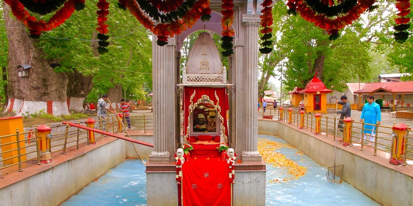 Interior of the Kheer Bhawani temple with god statues in a small shrine and the devotees