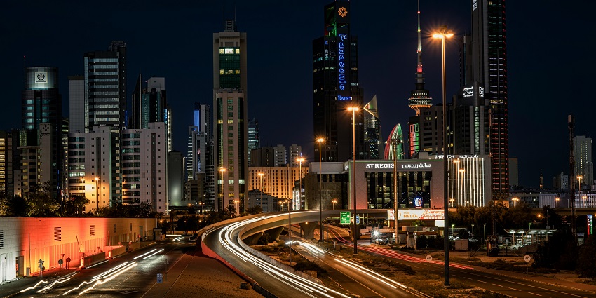 An image showing Kuwait downtown at night with bright city lights and busy streets.