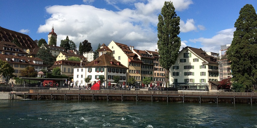 European cityscape along a river with historic buildings and a cathedral with twin spires