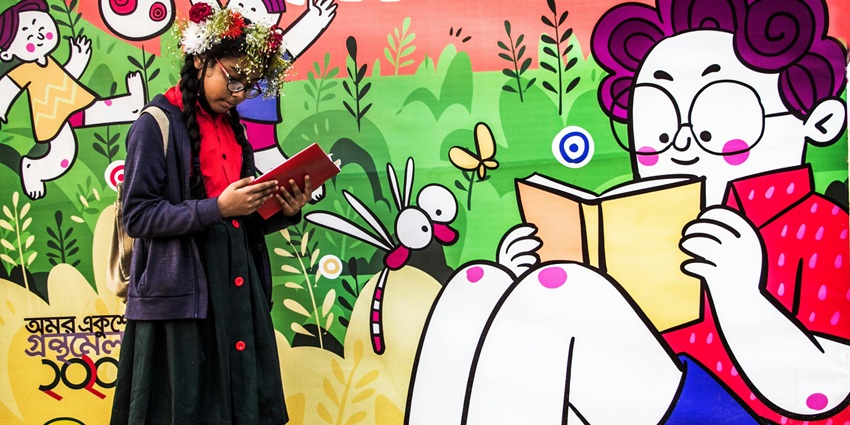 A girl reading a book in front of a wall with paintings and murals in Malbun Youth Center, one of the best places to visit in Malbun.
