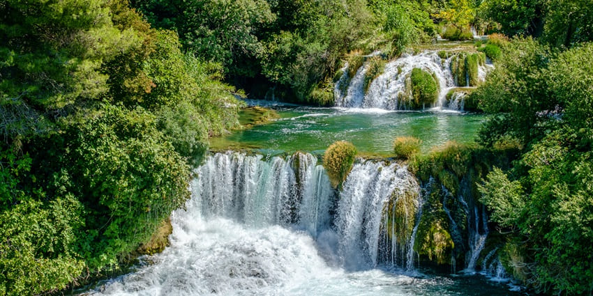 The jaw-dropping waterfalls in the middle of the green landscape on a perfect day.