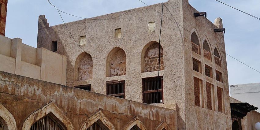 Historic Siyadi House with intricate lattice windows and wind tower in Muharraq