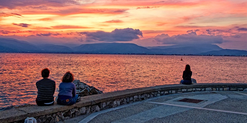 Three females enjoying a lovely sunset at Nafplio, a seaside place to visit near Athens.