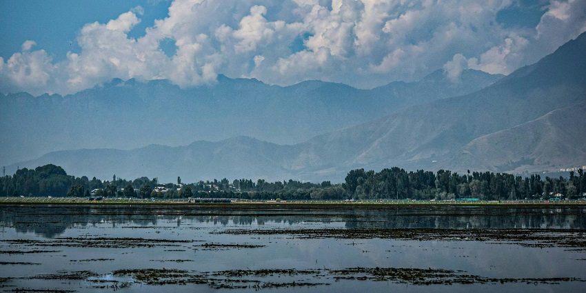 Wular lake, with a large and still-water body, and multiple people rowing in the boats