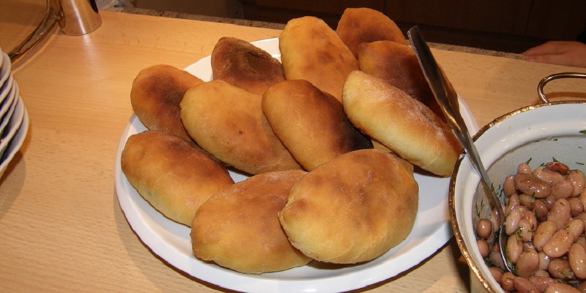 A tray of baked or fried Pirozhki, stuffed pastries with various fillings, a top food in Russia.