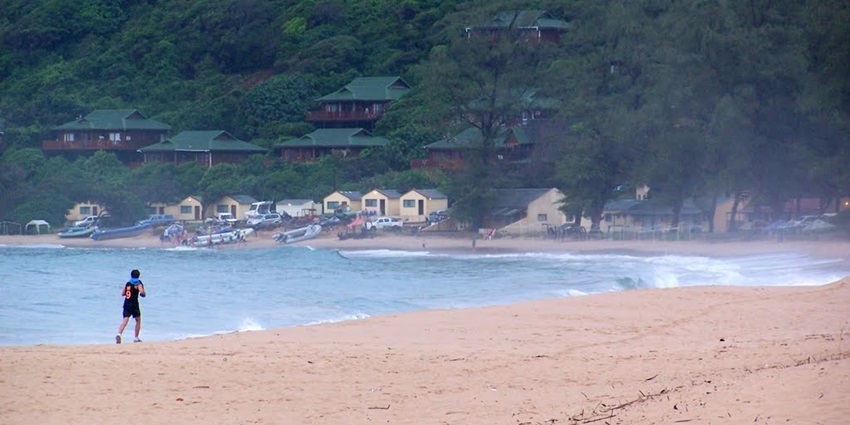Ponta do Ouro beach at dawn, golden sand, gentle waves beneath cloudy sky.