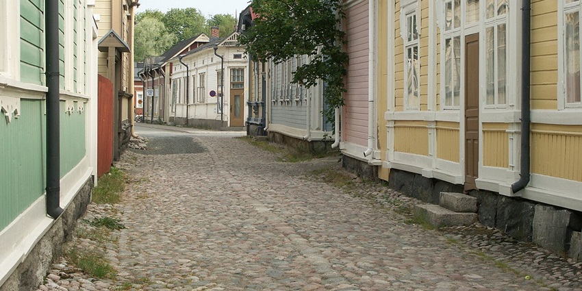 Pedestrian cobblestone street flanked by colorful wooden houses in Old Rauma, Finland