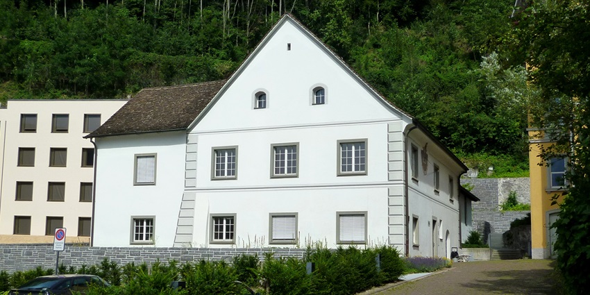 A glimpse of the Rheinbergerhaus in Liechtenstein surrounded by lush greenery.