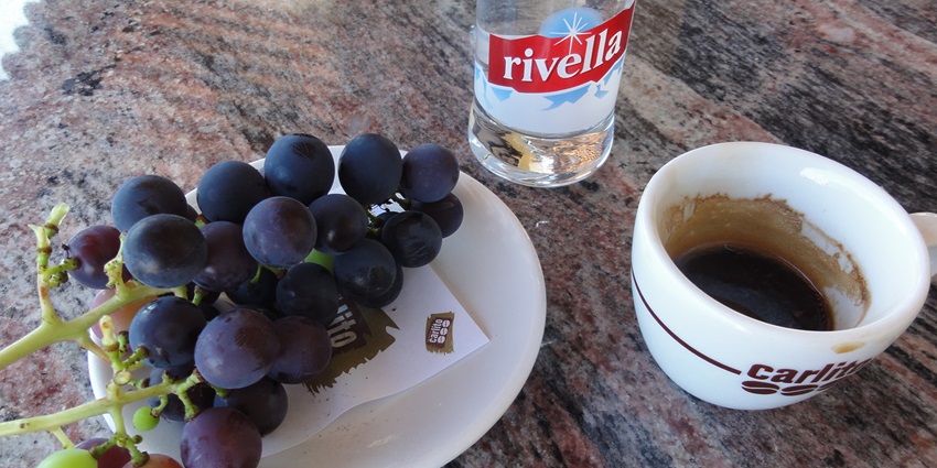 An image showing Ticino's Caffé Carlito, fresh grapes, and a bottle of Rivella beverage.
