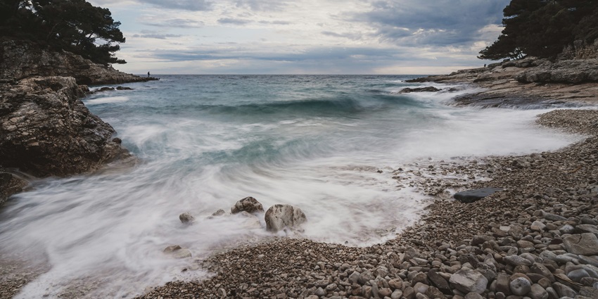 Scenic rock beach with clear blue water and sunny sky, perfect for relaxing.