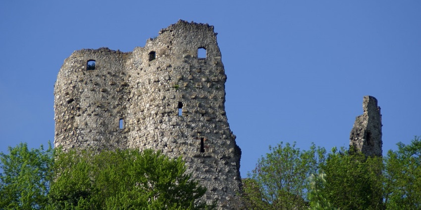 Ruins of Pfeffingen Castle standing on a green hilltop under a bright blue summer sky