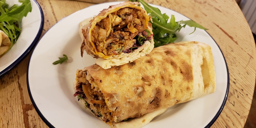 A pair of half-cut Chicken Shawarma Wraps is served on a plate at a restaurant in Toronto.