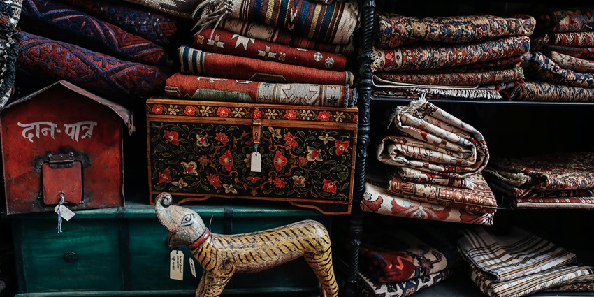 Stacks of vibrant, colorful fabric neatly arranged on wooden shelves in a boutique-style shop, perfect for artisan shopping experiences.