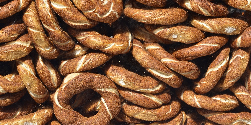 Fresh Simit bread slices loaded with sesame seeds and heaped together for sale.