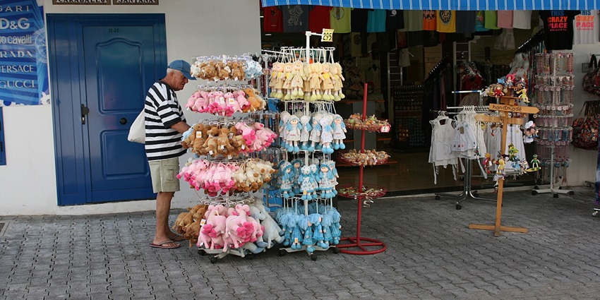 Pedestrian shopping street in Playa Blanca lined with boutiques, cafés, and palm trees, with people strolling and browsing
