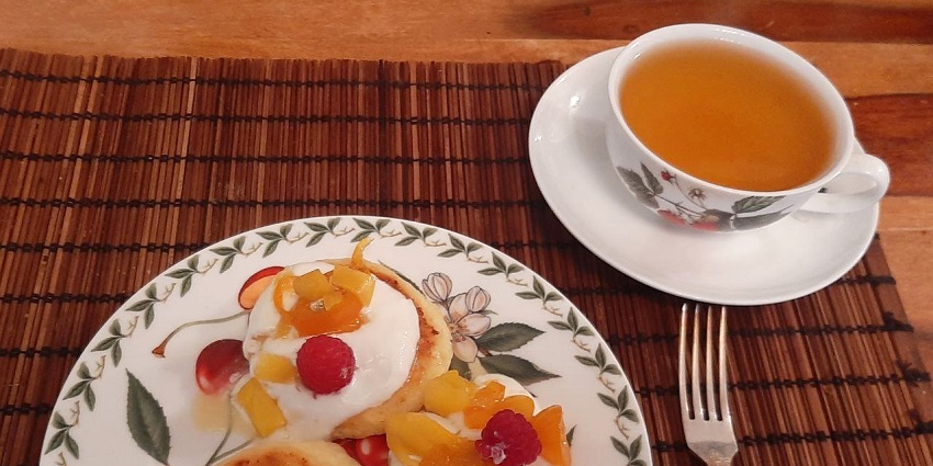 A plate of Syrniki, golden-brown cheese pancakes served with honey, the best food in Russia.