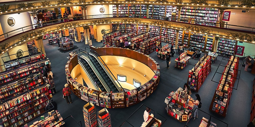 Lavish bookstore inside a former theater with velvet curtains, ornate balconies, and rows of books under a frescoed dome.