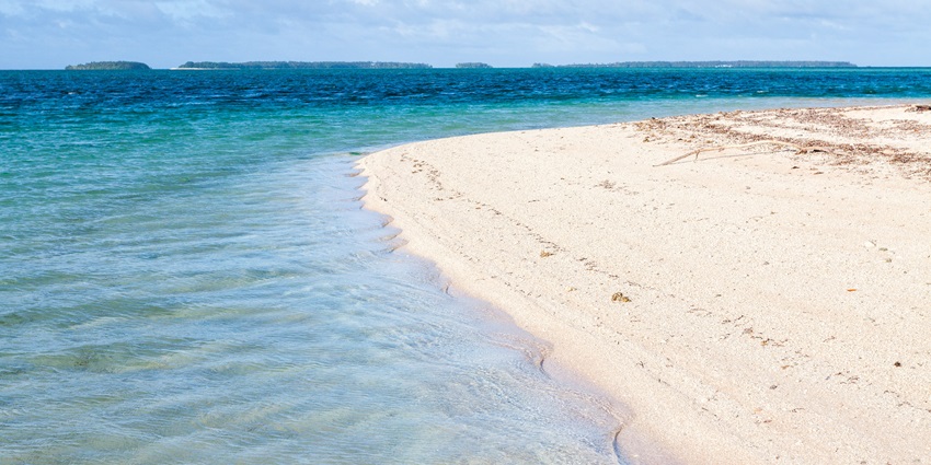 A peaceful beach with soft white sand and clear turquoise water at Laura Beach.