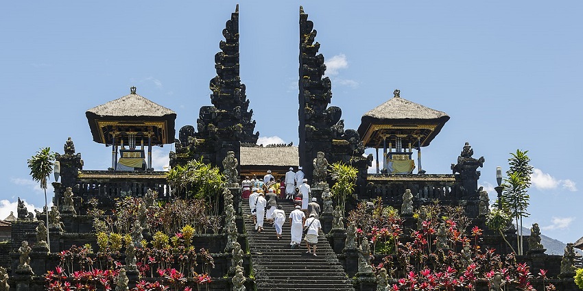 Golden Buddha statue and intricately carved temple structures surrounded by manicured gardens at Mahavihara Buddhamanggala in Balikpapan.